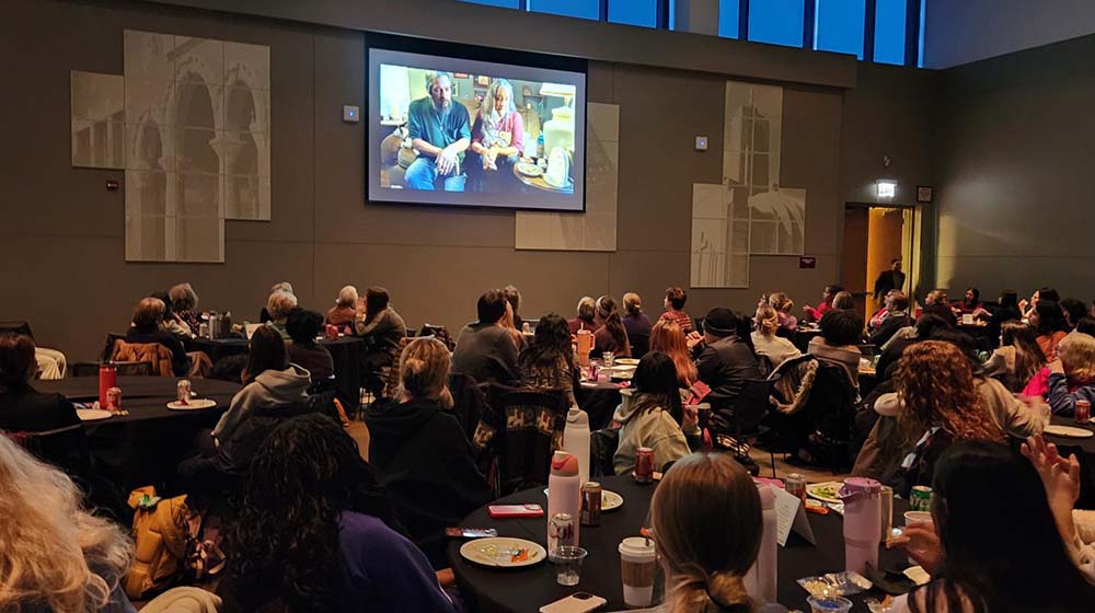 A crowd sits at the Damen Center and watches a documentary